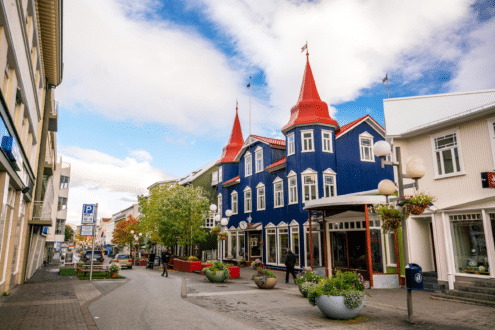 A street view of Akureyri, North Iceland with a blue house with a red roof in the foreground.