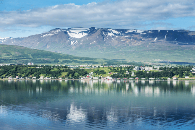 Une vue sur la ville d'Akureyri dans le nord de l'Islande, une puissante montagne en arrière-plan et l'océan en face.