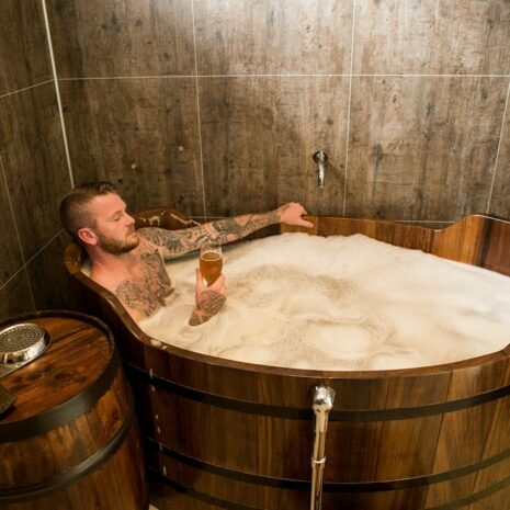 Un homme trempant dans une baignoire remplie d'une bière, tenant un verre de bière au Beer Spa dans le nord de l'Islande