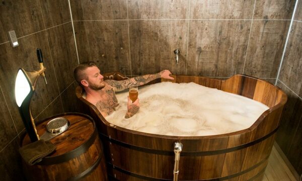 Un homme trempant dans une baignoire remplie d'une bière, tenant un verre de bière au Beer Spa dans le nord de l'Islande