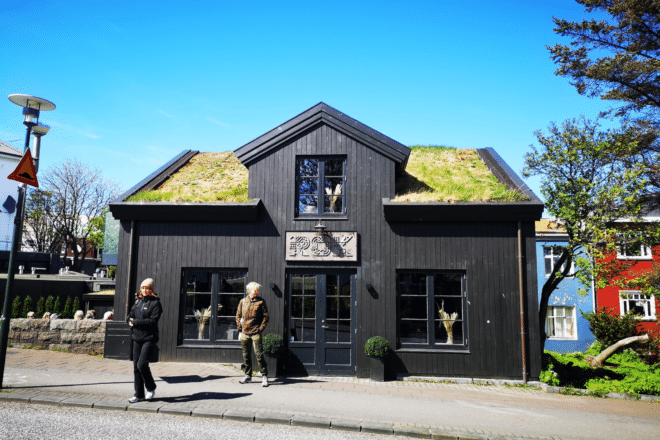 A restaurant in Reykjavik in a black building with a turf roof, blue sky