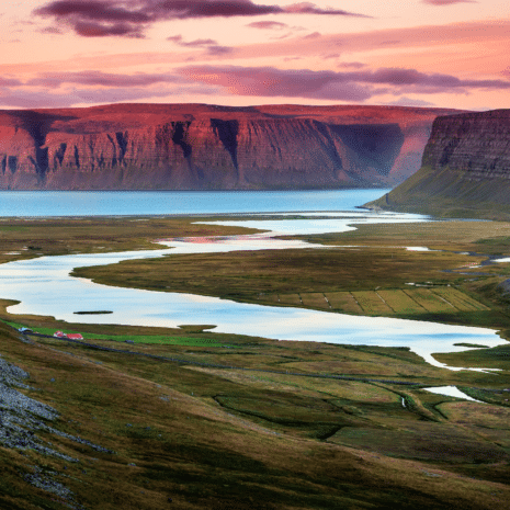 Pink skies at sunset over mountains and ocean in the Westfjords of Iceland.