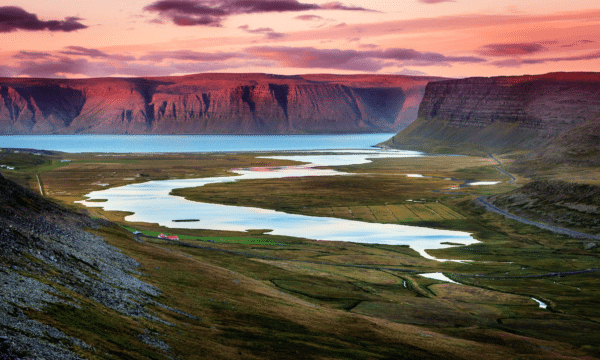 Cielos rosas al atardecer sobre las montañas y el océano en los fiordos del oeste de Islandia.