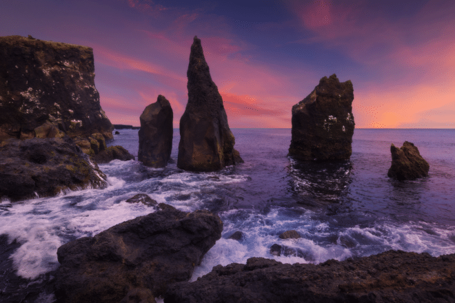 Group of sea stacks at sunset with cloudy pink sky in the background, Reykjanes peninsula, Iceland