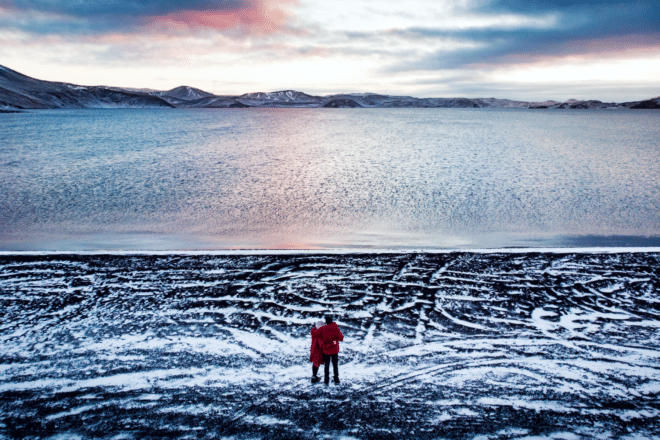 Un couple debout sur les rives enneigées du lac Kleifarvatn sur la péninsule de Reykjanes, en Islande.