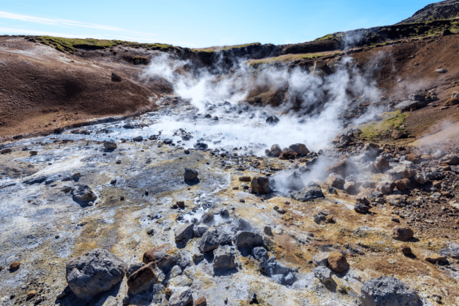 Steam rising from blue, bubbling mud pools at Seltún on the Reykjanes Peninsula, Iceland.