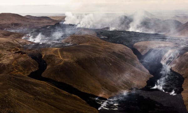 Aerial view of steam rising from a black lava field from Fagradalsfjall Volcano, Iceland.