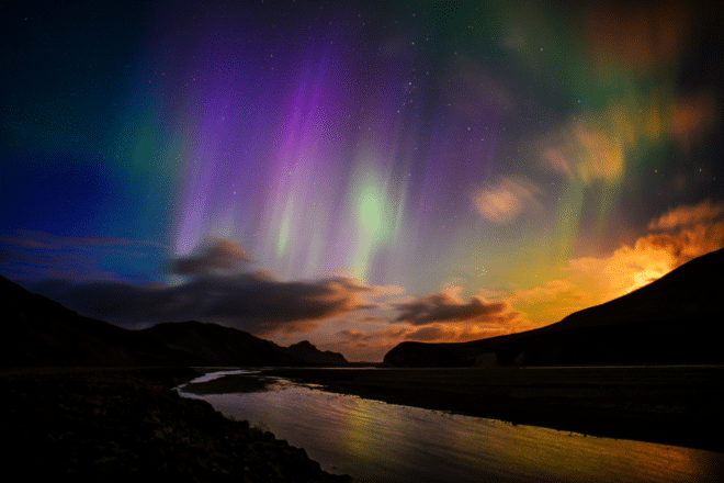 Aurora Borealis, o Northern Lights, revoloteando sobre un río y el paisaje volcánico de Landmannalaugar, Reserva Natural de Fjallabak, Tierras Altas Centrales, Islandia
