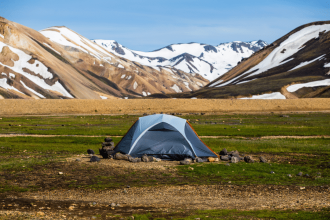 Surreal icelandic volcanic mountain with hiker tent, 4x4 vehicle camping on campsite in summer at central of Iceland