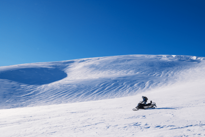 Un homme conduit une motoneige dans une journée ensoleillée, Islande