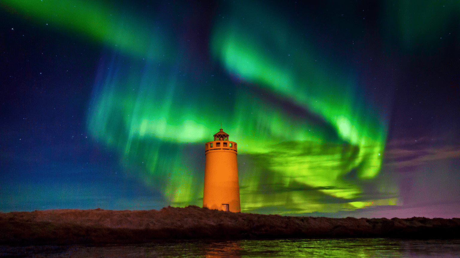 A lighthouse in Iceland under the Northern Lights.