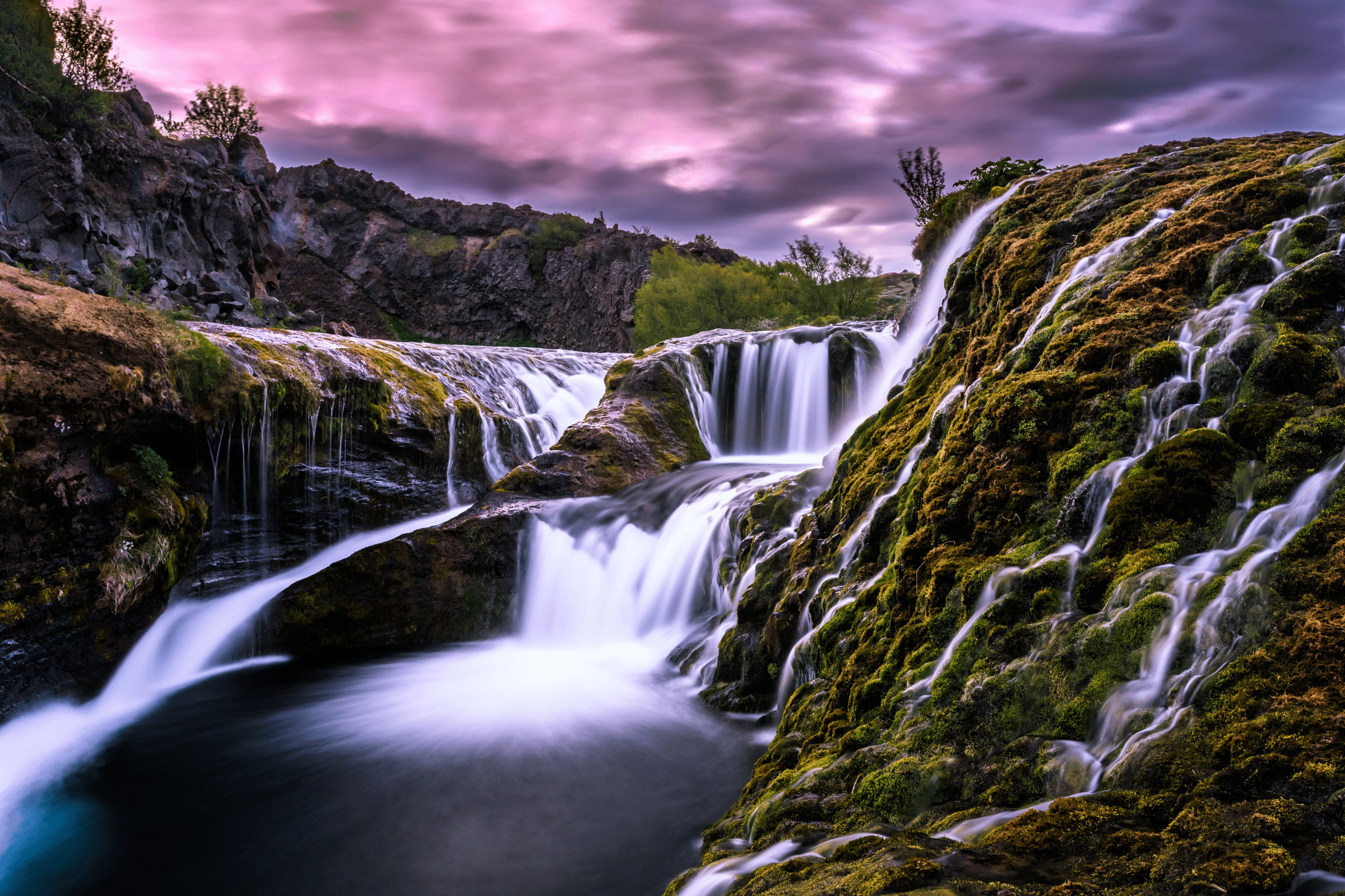 Gjain Waterfall and Canyon in South Iceland under pink skies.