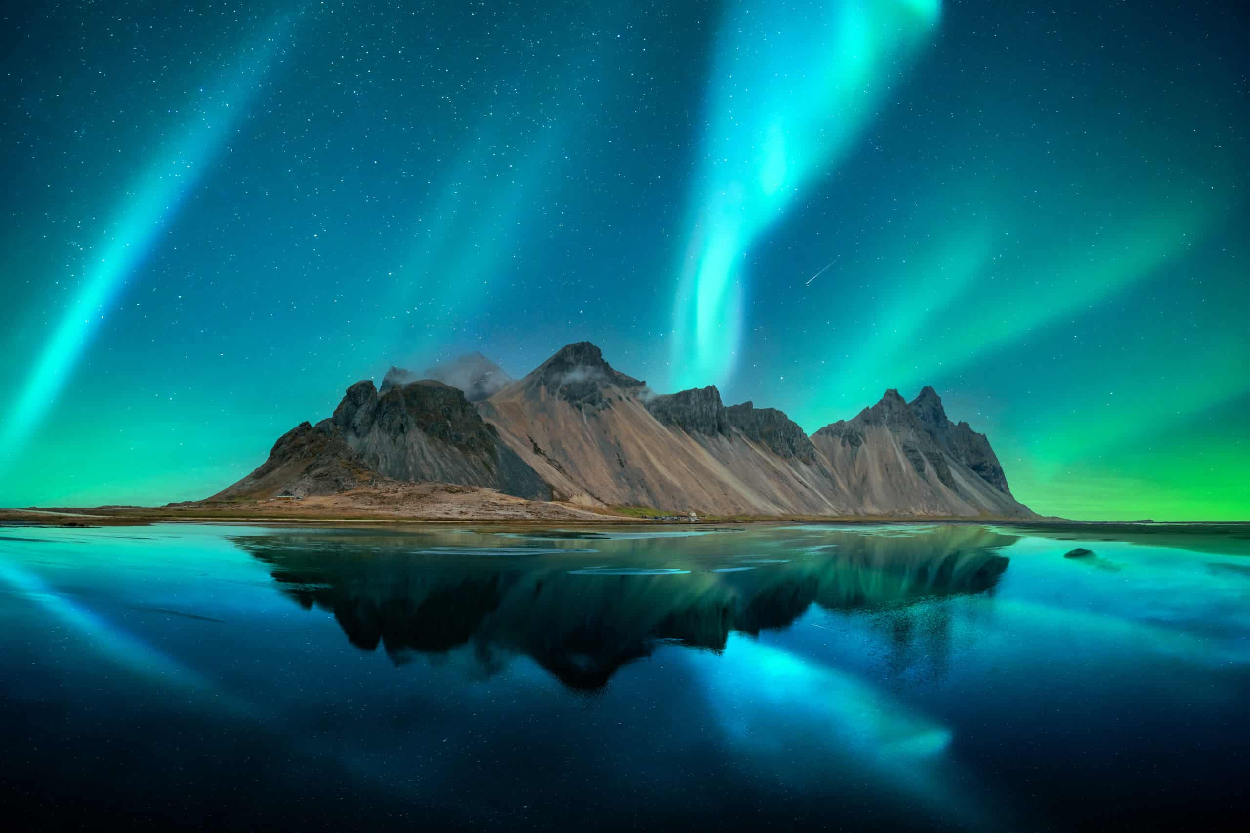 Aurora boreal sobre el monte Vestrahorn en la península de Stokksnes, reflejada en la playa de arena de abajo.