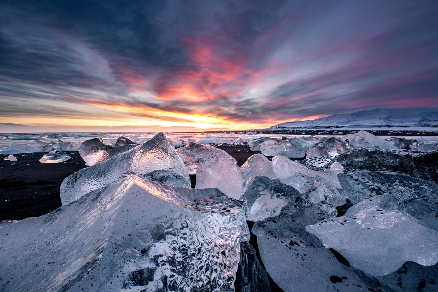 Icebergs sobre arena negra al atardecer en la playa Diamond Beach de Islandia.