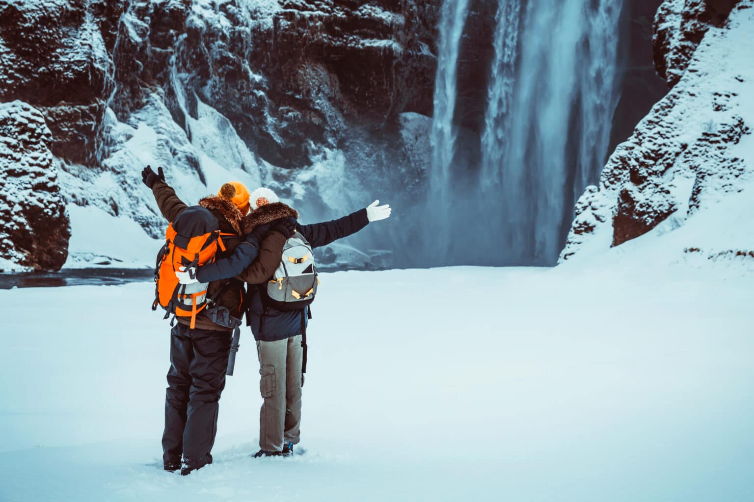 Heureux couple devant la cascade de Skógafoss, dans le sud de l'Islande, en hiver.