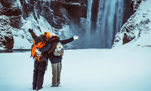 Heureux couple devant la cascade de Skógafoss, dans le sud de l'Islande, en hiver.