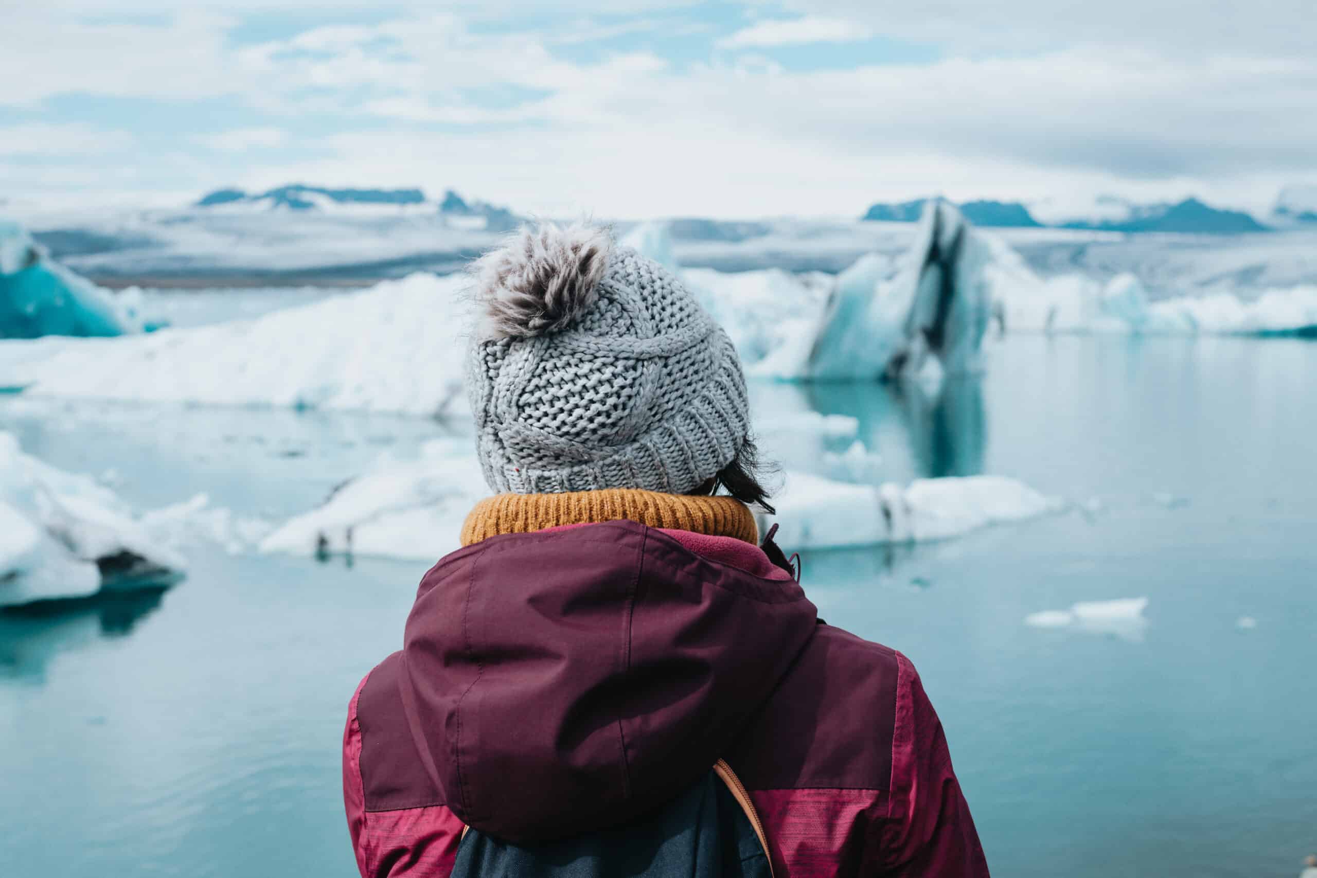 A woman standing in front of ice bergs on Jökulsárlón Glacier Lagoon, Iceland.