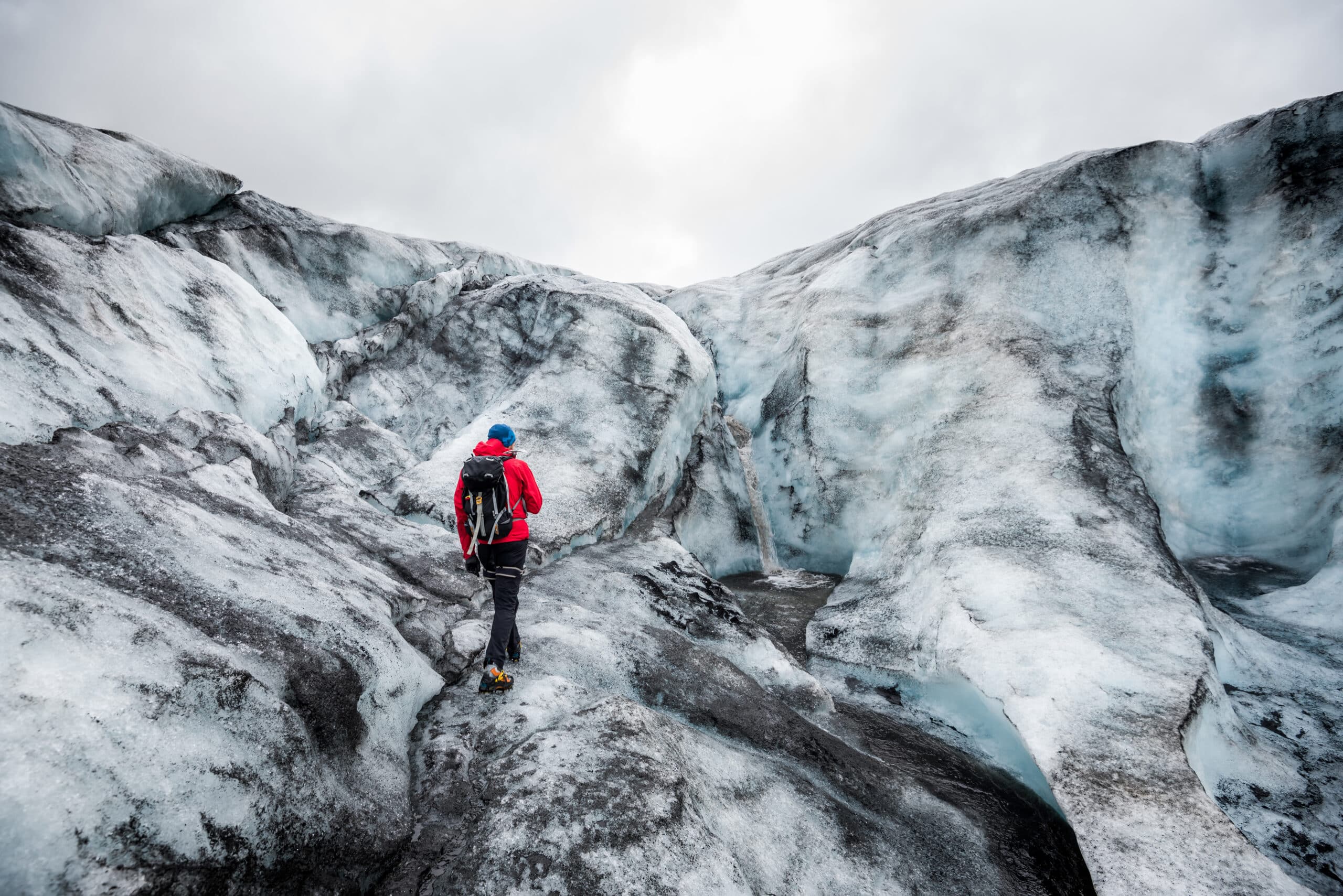 Un hombre caminando por un glaciar cubierto de ceniza en el sur de Islandia.