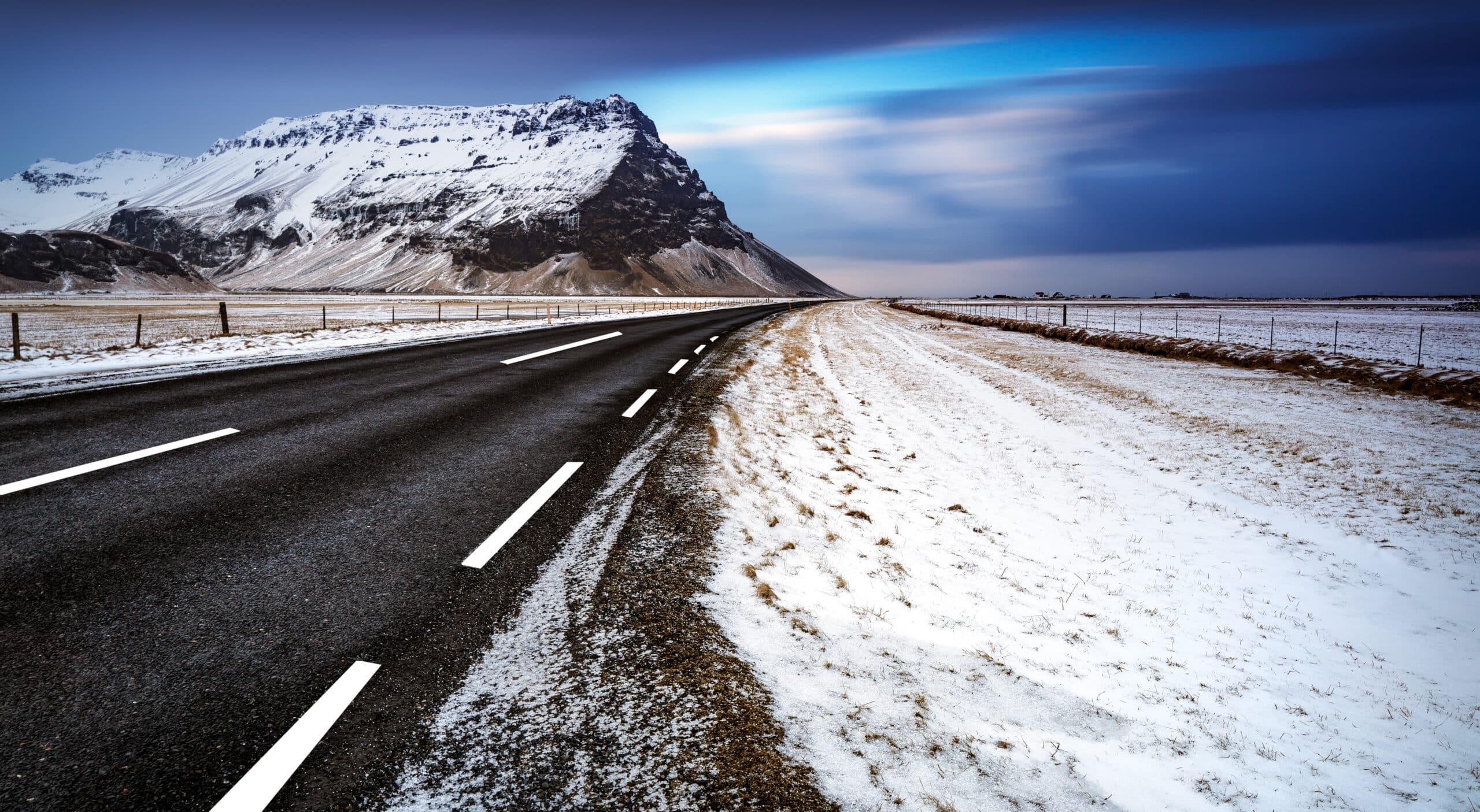 Hermoso paisaje invernal de una carretera, carretera vacía, vista tranquila de la gran montaña cubierta de nieve, invierno en Islandia.