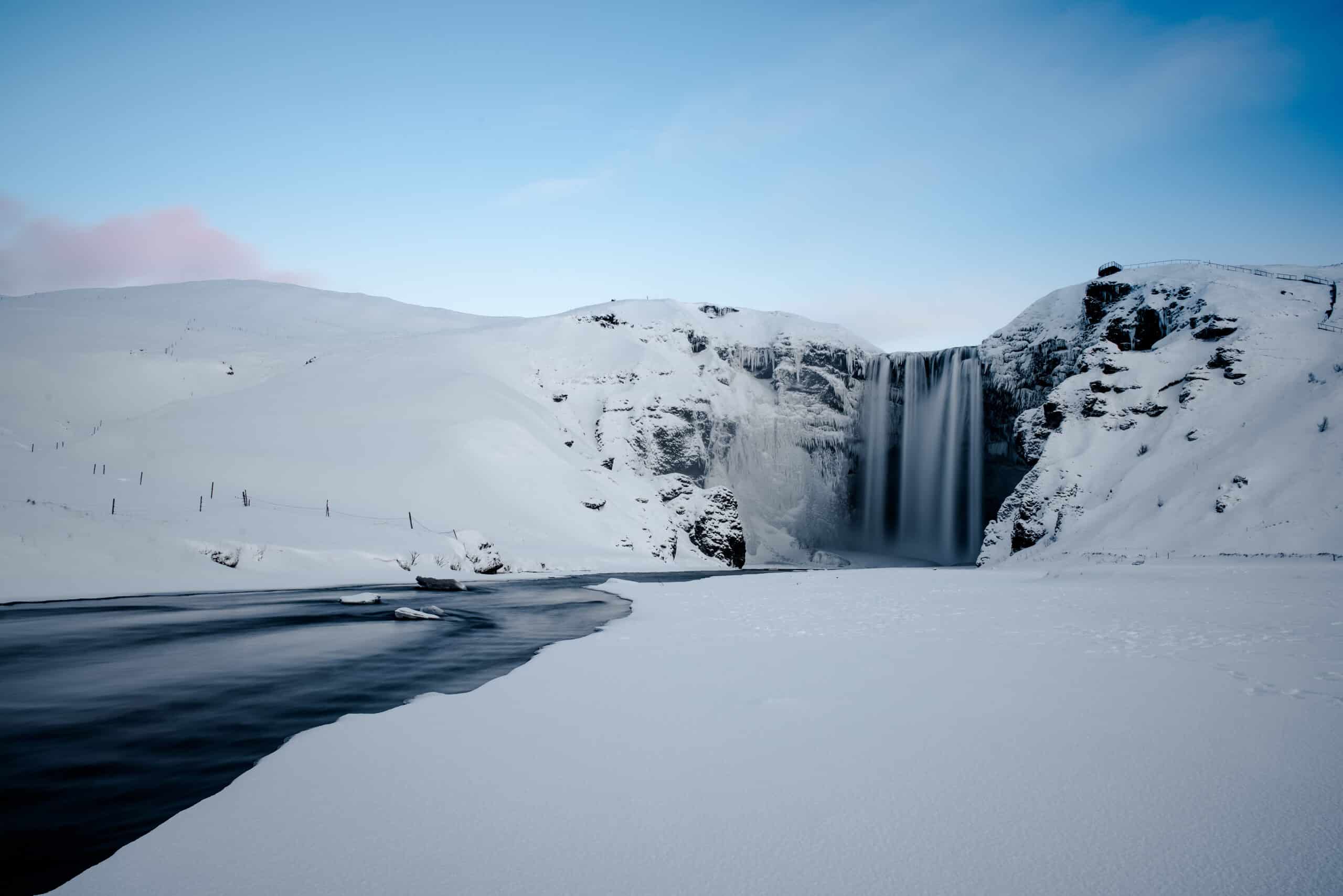 A winter scene in Iceland of Skogafoss Waterfall surrounded by snow.
