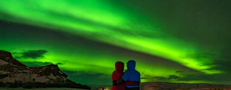 La aurora boreal brilla sobre una pareja que viaja
