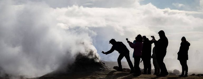 Grupo de personas tomando fotografías de una fumarola en el norte de Islandia