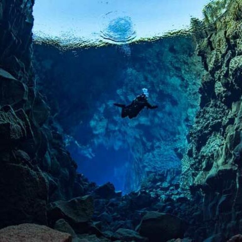 Un plongeur dans la fissure de Silfra en Islande sur la route touristique du Cercle d'Or.