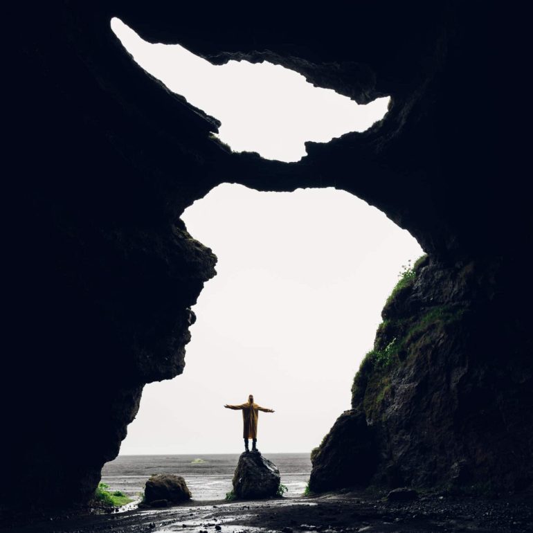 A man standing inside "Yoda Cave", Hjörleifshöfði Cave in Iceland.