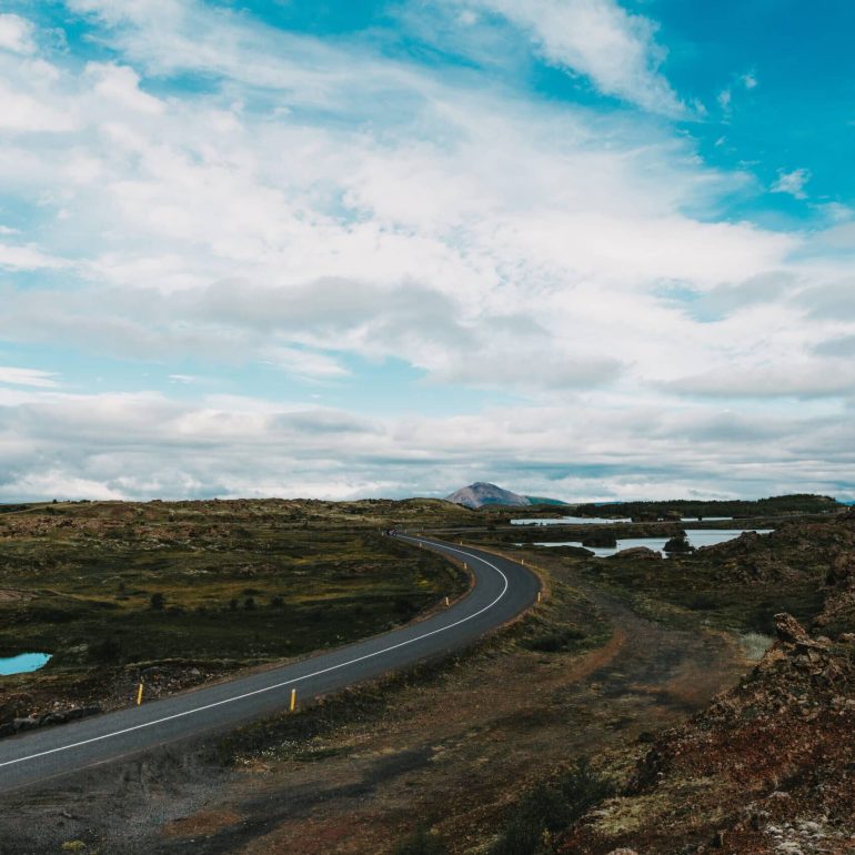 Empty asphalt road winding through the lava fields of Iceland's Reykjanes Peninsula.