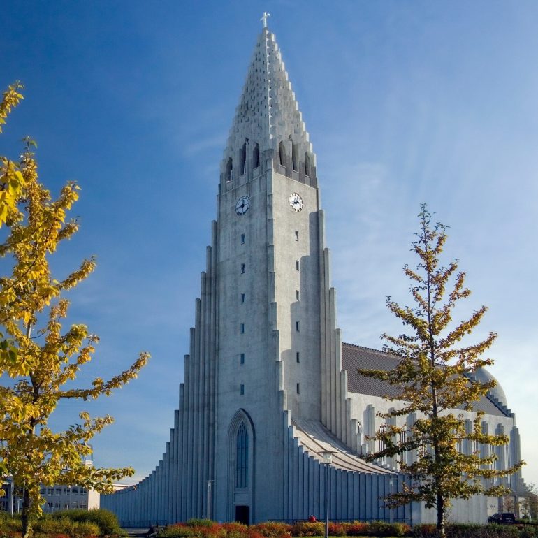 Iglesia Hallgrimskirkja en Reykjavik, Islandia en un día de verano's. Árbol en primer plano, cielos azules.