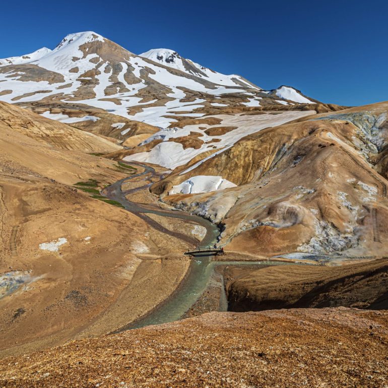A river between snow-capped Kerlingarfjöll mountains in the Icelandic Highlands, summer.