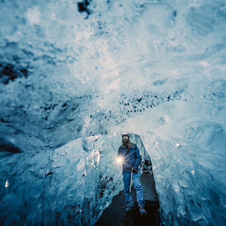 A man inside a blue ice cave in Vatnajokull National Park, Iceland.